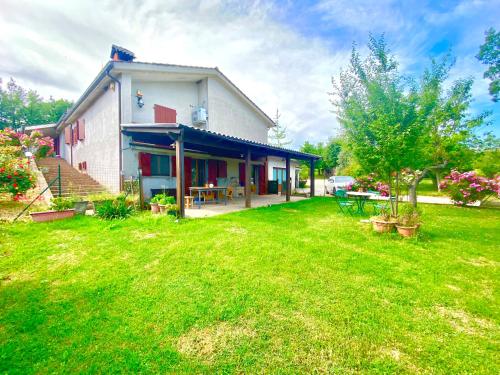 a house with a yard with a grass field at Villa Strada dei Monti Sibillini in Montefortino