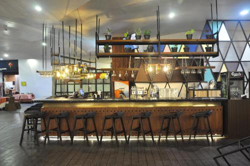 a bar with a bunch of stools in a room at Golden Tulip Pontianak in Pontianak