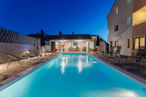 een zwembad met stoelen en een huis bij Residence Ellena in Zadar