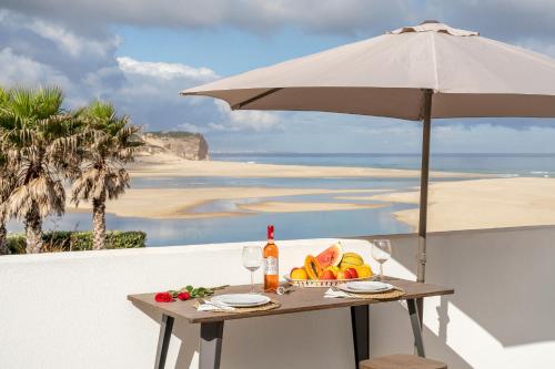 a table with a bowl of fruit and an umbrella at Foz Beach House - Rooftop & Sea view in Foz do Arelho