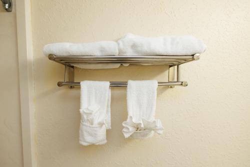 a towel rack with white towels on a wall at Garnet Inn & Suites, Orlando in Orlando