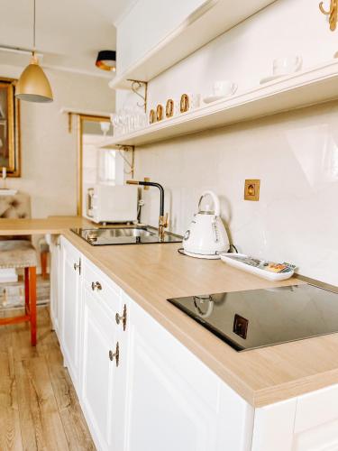 a kitchen with white cabinets and a tea kettle on a counter at Apartmán Opera Prosecco Bar in Banská Štiavnica