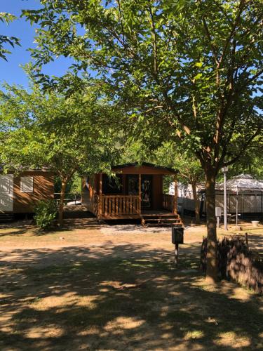 a log cabin with a porch under a tree at Càmping Molí de Vilamala in Les Planes d'Hostoles