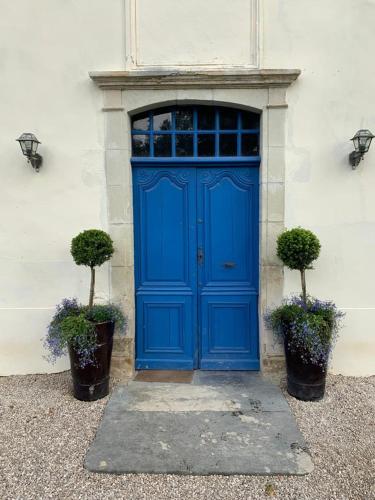une porte bleue sur un bâtiment blanc avec deux plantes dans l'établissement Elegant and Spacious Maison de Maitre Ideal for Group Bookings, à Samadet