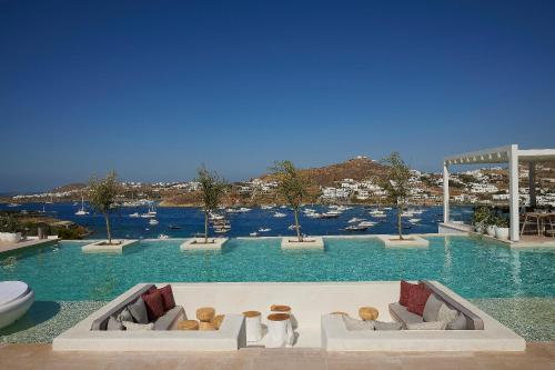 a large pool with blue water with two couches at Once in Mykonos - Designed for Adults in Ornos
