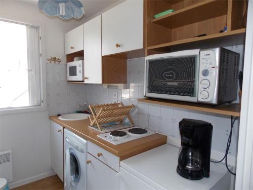 une petite cuisine avec un micro-ondes et une cuisinière dans l'établissement T2 avec parking proche thermes - FR-1-313-135, à Luchon