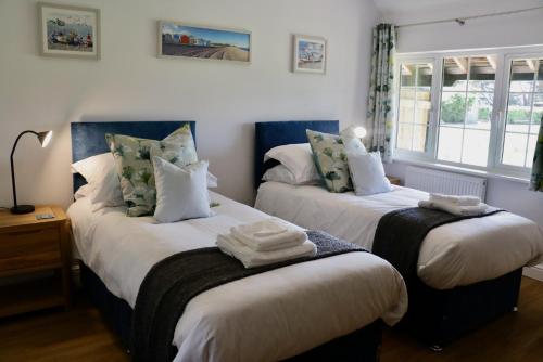 2 camas en una habitación con 2 ventanas en Lawnside 1 en Budleigh Salterton