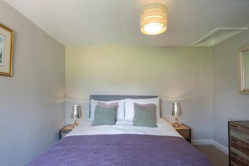 a bedroom with a large bed with purple sheets and pillows at Rose Cottage, Eden Valley, Cumbria in Cumwhitton