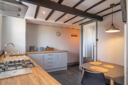 a kitchen with white cabinets and a table and a stove at Rose Cottage, Eden Valley, Cumbria in Cumwhitton