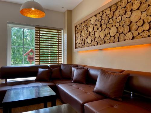 a living room with a brown leather couch and a window at Friesenhof Hotel-Restaurant-Reitanlage in Trassenheide