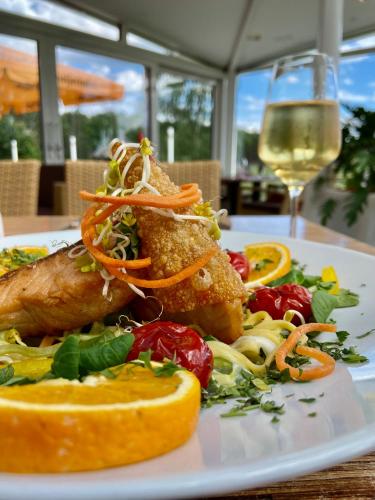a plate of food on a table with a glass of wine at Friesenhof Hotel-Restaurant-Reitanlage in Trassenheide