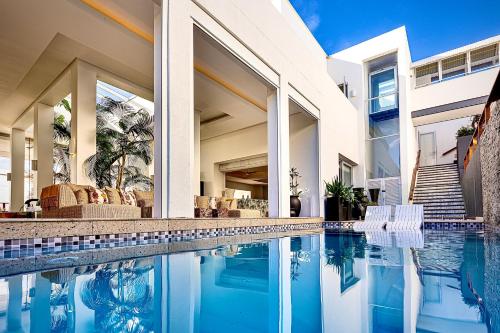 a swimming pool in front of a house at Dolphin Coast YOLO Spaces - The White House Boutique Villa in Sheffield Beach
