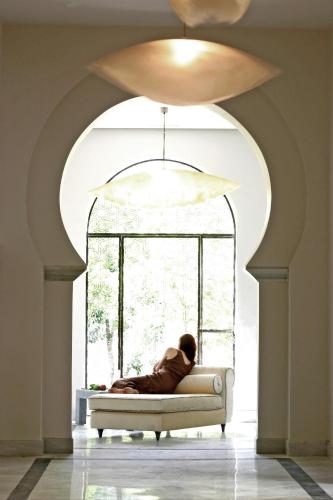 a person sitting on a couch in front of a window at Hospes Palacio del Bailio, a Member of Design Hotels in Córdoba