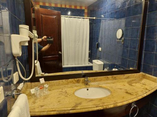 a person taking a picture of a bathroom sink at فندق بورتو مارينا - غرفة فندقية بخدمة فندقية in El Alamein