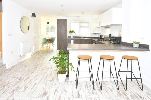 a kitchen with three bar stools and a counter at Ivory House by Truestays - 3 Bedroom House in Stoke-on-Trent in Etruria