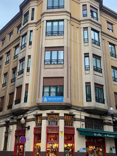 een hoog gebouw met veel ramen aan een straat bij Alojamientos Muelle de Gijón in Gijón