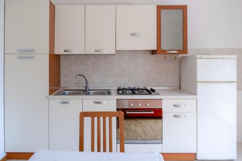 a kitchen with white cabinets and a sink and a stove at Incantevole appartamento con parcheggio gratuito in Trento