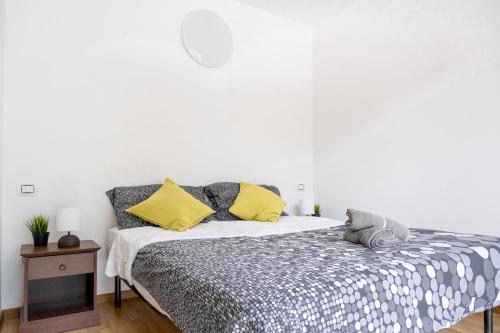 a bedroom with a bed with yellow and gray pillows at Incantevole appartamento con parcheggio gratuito in Trento