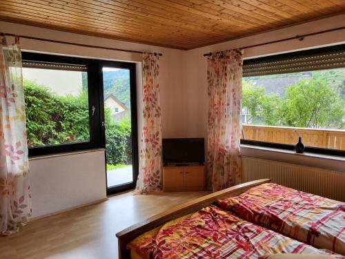 ein Schlafzimmer mit einem Bett und zwei großen Fenstern in der Unterkunft Ferienwohnung zum Rheinblick in Kestert