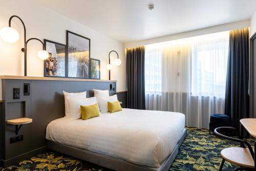 a hotel room with a large bed with yellow pillows at Best Western M-Treize Paris Asnieres in Asnières-sur-Seine