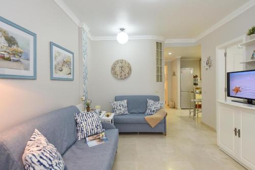 a living room with a blue couch and a tv at Apartment Las Canteras Beach in Las Palmas de Gran Canaria