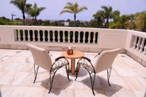 a table and chairs on a patio with palm trees at THE WHITE PALACE Rabat in Rabat