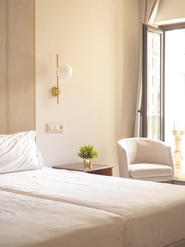 a bedroom with a white bed and a chair at Hotel Oriente in Zaragoza