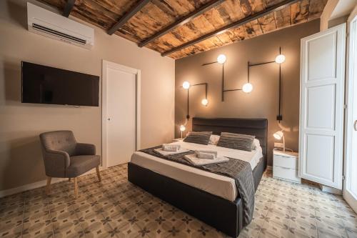 1 dormitorio con 1 cama y 1 silla en Palazzo Paladini - Luxury Suites in the Heart of the Old Town, en Pizzo