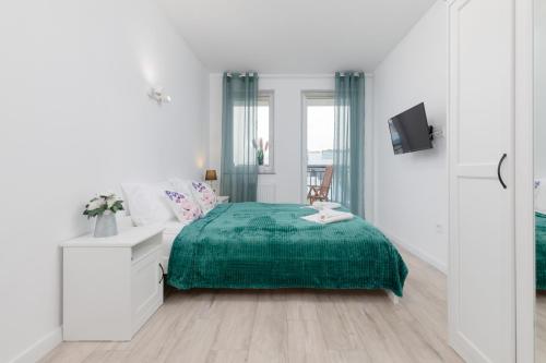 a white bedroom with a green bed and a desk at Morska Apartment Dziwnówek by Noclegi Renters in Dziwnówek