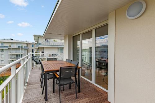 d'une terrasse avec une table et des chaises en bois sur un balcon. dans l'établissement Superbe appartement neuf avec un grand balcon - Cabourg - Welkeys, à Cabourg