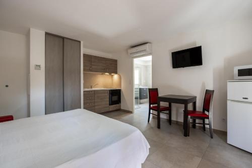 a bedroom with a bed and a table and chairs at The Originals City, Hôtel Les Bastides du Gapeau in Solliès-Toucas