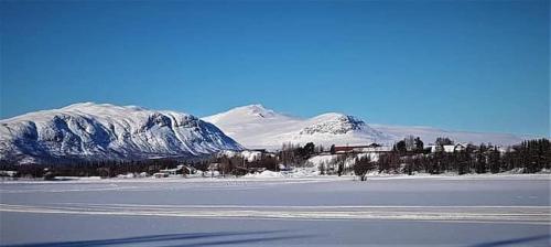 a snow covered field with a mountain in the background at Kultsjögården-Saxnäs- Marsfjäll 10 in Saxnäs