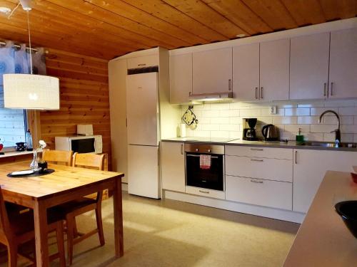 uma cozinha com armários brancos e um tecto de madeira em Kultsjögården-Saxnäs- Marsfjäll 10 em Saxnäs