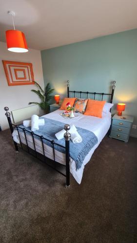 a bedroom with a large bed with orange pillows at The Kingfisher, by Spires Accommodation a great location for visiting the NEC and Drayton Manor in Kingsbury