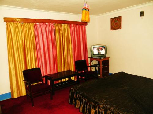 a bedroom with a bed and chairs and a television at Hotel Dewachan in Pituk