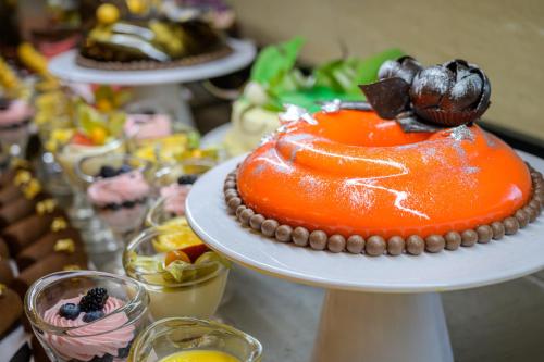 an orange cake on a white plate with other desserts at Effect Algara Beach Resort - Ultra All Inclusive and Free Parking in Kranevo