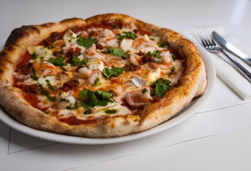 a pizza sitting on a plate on a table at Hotel Bellotto in Warsaw