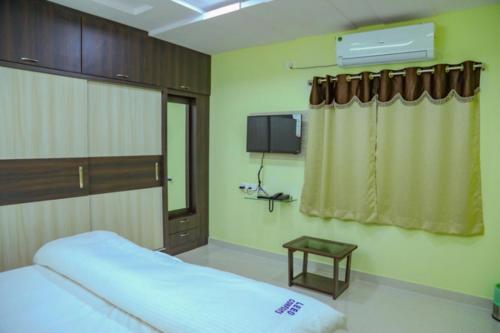 1 dormitorio con 1 cama y TV en la pared en Leeo Comforts en Visakhapatnam