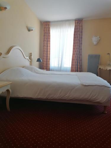 a large bed in a bedroom with a window at Hôtel l'Arena in Fréjus