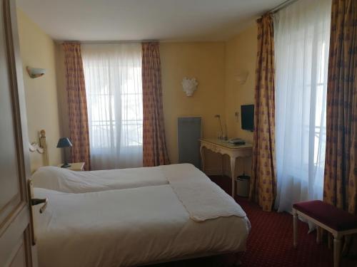 a hotel room with a bed and a desk and window at Hôtel l'Arena in Fréjus