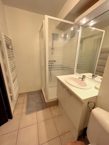 une salle de bain blanche avec un lavabo et une douche dans l'établissement Un brin de Sud, à Arles