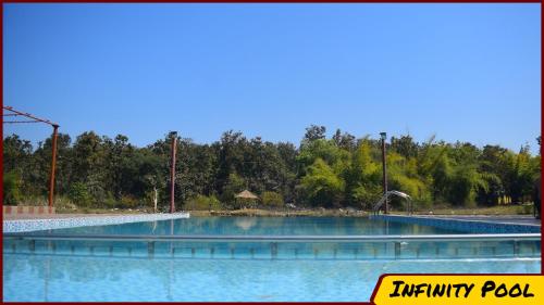 una gran piscina de agua con árboles en el fondo en Kanha Resort, en Kānha