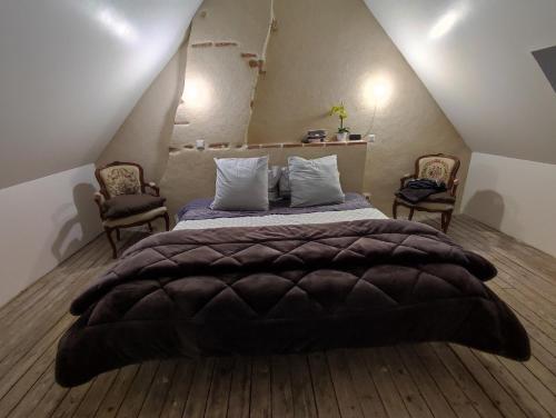 - une chambre avec un grand lit et 2 chaises dans l'établissement Bienvenue à La Grenouillère, à Le Magny