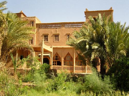 a large house with palm trees in front of it at Kasbah Itrane in Tamnougalt