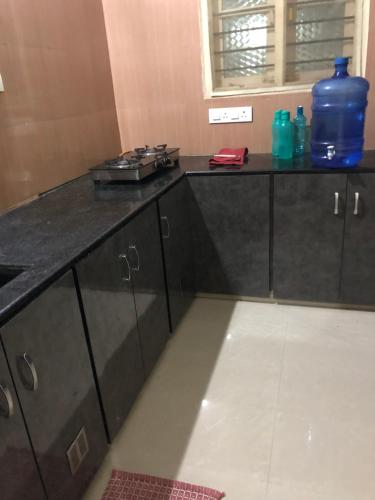 a kitchen with a black counter top with bottles on it at GIRI Service Apartment in Tirupati