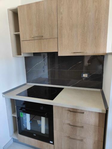 a kitchen with a black stove and wooden cabinets at Fantasia B&B APARTAMENT STUDIO in Pellaro