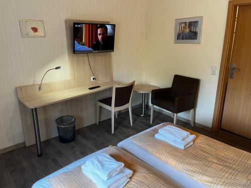 a hotel room with a bed and a desk and a television at Gästehaus 2 Norden in Norden