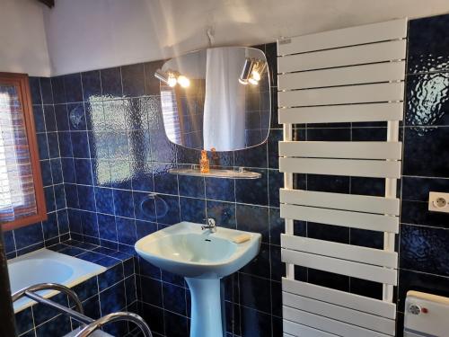 La salle de bains est pourvue de carrelage bleu, d'un lavabo et d'un miroir. dans l'établissement La Villa des Quatre PLAGES à la Seyne-sur-Mer, à La Seyne-sur-Mer