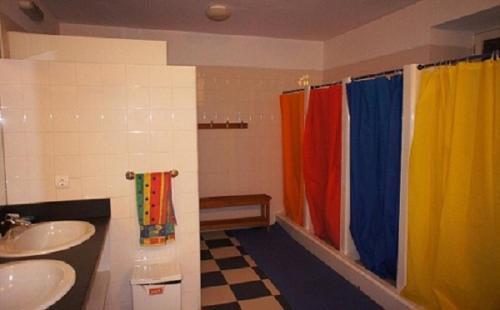 a bathroom with two sinks and a rainbow shower curtain at Stone Farm Hostel in Felgueiras