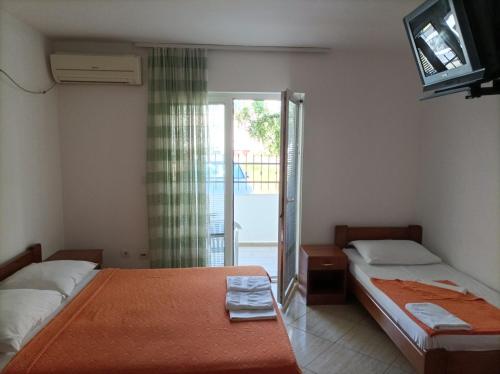 a bedroom with two beds and a television and a balcony at Apartmani Baštrica in Budva